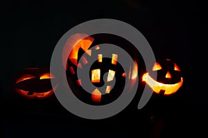 Halloween pumpkin background, three pumpkins with dark black background. Two scary faced pumpkins and house shaped