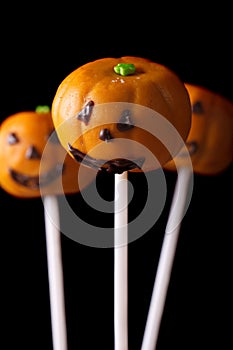 Halloween pumpkin cake pops isolated on a black. Vertical