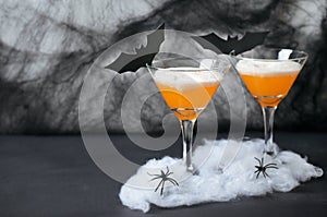 Halloween Pumpkin Cocktail, Toxic Orange Drink Decorated with Spiders, Cobweb and Black Bats on Dark Background