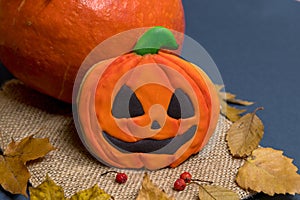 Halloween pumpkin cookie lies on burlap by real pumpkin