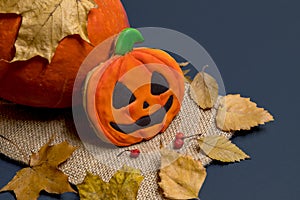 Halloween pumpkin cookie lies on burlap by real pumpkin