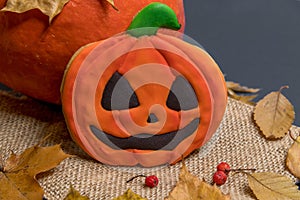 Halloween pumpkin cookie lies on burlap by real pumpkin