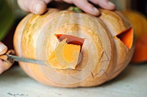 Halloween pumpkin cutting process, process of making Jack-o-lantern. Male hands with knife.