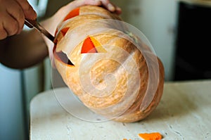 Halloween pumpkin cutting process, process of making Jack-o-lantern. Male hands with knife.