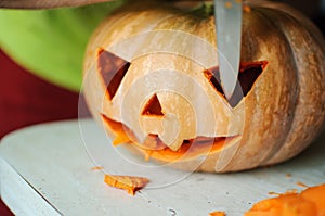 Halloween pumpkin cutting process, process of making Jack-o-lantern. Male hands with knife.