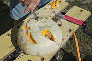 Halloween pumpkin cutting process, process of making Jack-o-lantern. Male hands with knife, leftovers of pumpkin on the kitchen