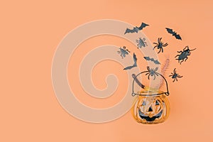 Halloween pumpkin with decorations on orange background.