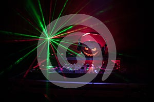 Halloween pumpkin on a dj table with headphones on dark background with copy space. Happy Halloween festival decorations and music