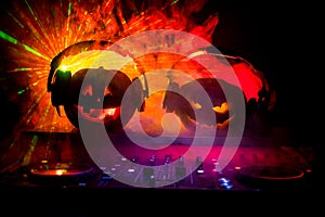 Halloween pumpkin on a dj table with headphones on dark background with copy space. Happy Halloween festival decorations and music