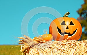 Halloween Pumpkin, funny Jack O'Lantern on Straw Bale over Sky.