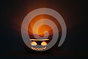 Halloween pumpkin with glowing face. Jack o lantern on a black background. Copy space