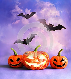 Halloween pumpkin head jack lantern with burning candles and black bats. Halloween concept