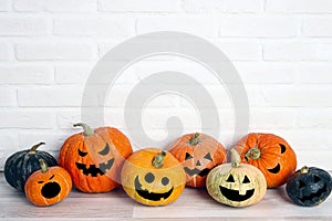 Halloween pumpkin head Jack lantern with funny faces on the table against a white brick wall background