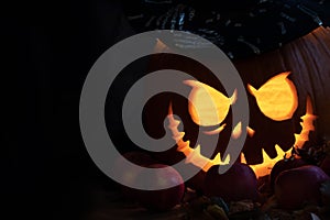 Halloween pumpkin head jack lantern with luminous eyes and mouth with candlelight on black background