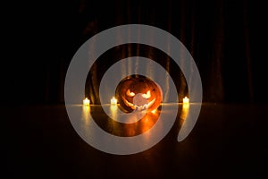 Halloween pumpkin head jack o lantern with glowing candles on background. Pumpkins on wooden floor