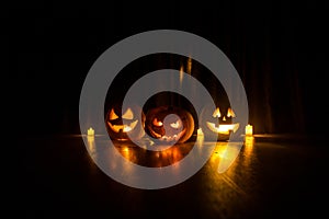 Halloween pumpkin head jack o lantern with glowing candles on background. Pumpkins on wooden floor