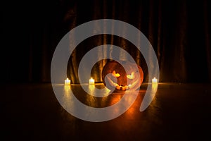 Halloween pumpkin head jack o lantern with glowing candles on background. Pumpkins on wooden floor