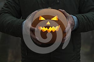 Halloween pumpkin head in male hands at night