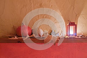 Halloween pumpkin heads, dry autumn leaves and burning jack lantern on wooden board in front painted wall background