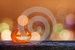 Halloween pumpkin Jack O`Lantern happy smiling face on grunge wood night bokeh