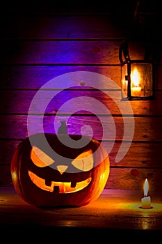 Halloween pumpkin with a lantern and a candle on wooden background