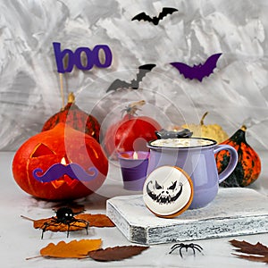 Halloween pumpkin and mug of coffee with cookies on the background of a gray wall with ghosts, bats, spiders, candles