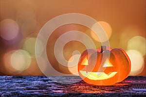 Halloween pumpkin orange Jack O`Lantern happy smiling face on grunge wood candle light lit bokeh for halloween party autumn