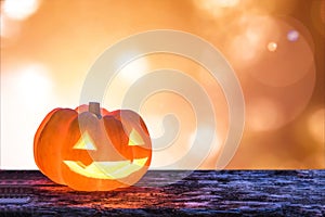 Halloween pumpkin orange Jack O`Lantern happy smiling face on grunge wood candle light lit bokeh for halloween party autumn