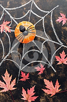 Halloween, pumpkin, spider, red maple leaves, spider web drawn in chalk on a dark rustic background. Top view,flat lay.