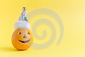 Halloween pumpkin wearing Santa Claus hat isolated on yellow.