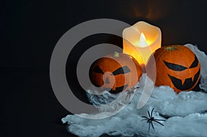 Halloween pumpkin on the web. Burning candle on a black background.