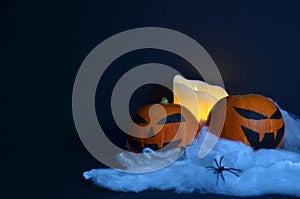 Halloween pumpkin on the web. Candle on a black background.