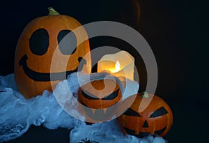 Halloween pumpkin on the web with spiders. Burning candle.