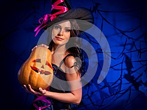Halloween pumpkin in witch woman hands.