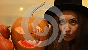 Halloween. Pumpkin. Woman in the black hat It expresses emotions with big eyes - surprise, fear, fright. Portrait close