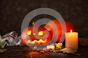 Halloween pumpkins with candies and candles on dark background