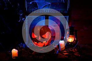 Halloween - pumpkins, candles and a lamp on leaves and logs with