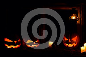 Halloween - pumpkins, candles and a lamp on leaves and logs, against the background of a window