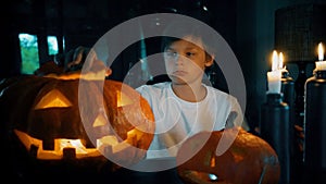 Halloween. pumpkins, candles, midnight. boy sitting next to the glowing pumpkins. HD cinemagraph