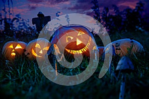 Halloween pumpkins lie on a pumpkin field at night with the eyes of the gears hours.