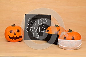 Halloween pumpkins in protective face masks and the inscription stop covid 19