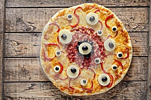 Halloween scary food monster pizza with eyes on vintage wooden table