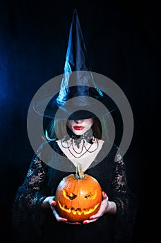 Halloween sexy witch with a magic pumpkin on black background