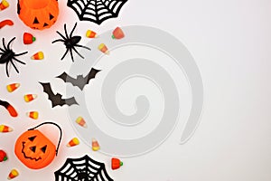 Halloween side border of candy and decor, flat lay over white