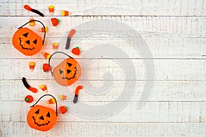 Halloween side border with Jack o Lantern pails and candy on white wood