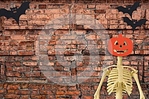 Halloween skeleton and bat on old red brick background