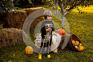 Halloween skeleton child. Boy sitting on the haystack. Little boy in skeleton costume playing in autumn park. Child