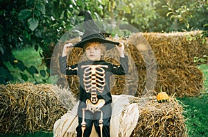Halloween skeleton child. Funny kid in carnival costumes outdoors. Portrait of happy smiling child boy on nature