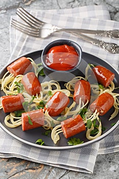 Halloween spiders dish of spaghetti with sausages and ketchup close-up in a plate. Vertical