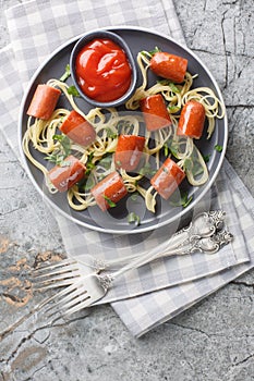 Halloween spiders dish of spaghetti with sausages and ketchup close-up in a plate. Vertical top view